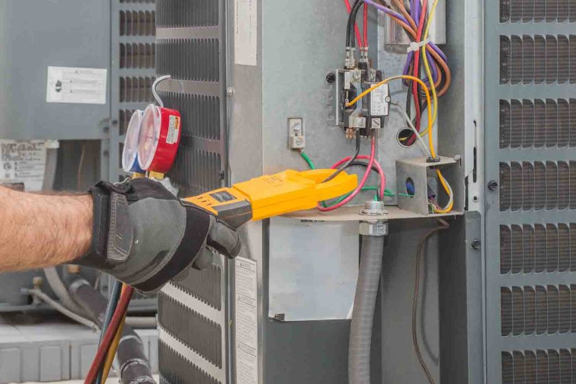 Professional hvac technician measuring amperage on an air conditioner unit